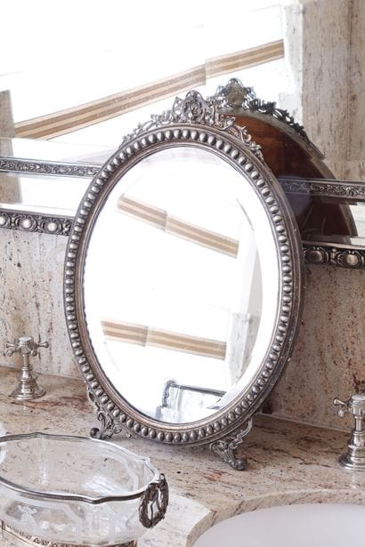 Miroir ovale biseauté cerclé de métal argenté...