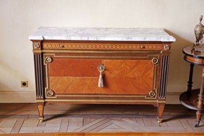 A veneered wood chest of drawers featuring...