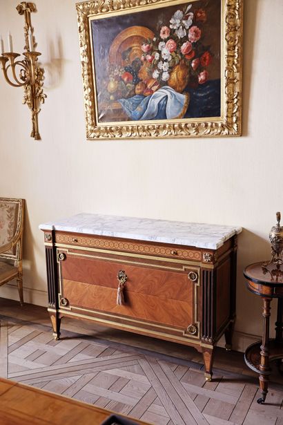 A veneered wood chest of drawers featuring...