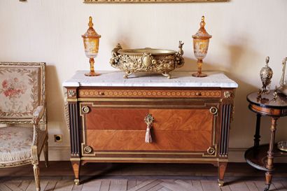 A veneered wood chest of drawers featuring...