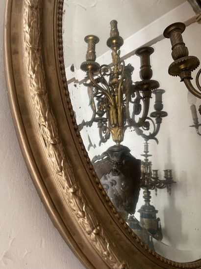 Miroir ovale en bois stuqué et redoré. Le...