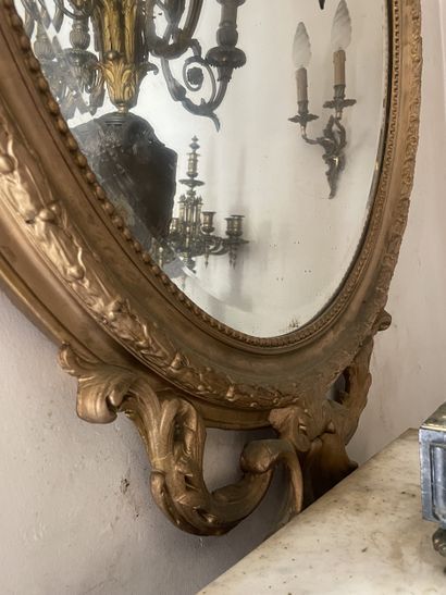 Miroir ovale en bois stuqué et redoré. Le...