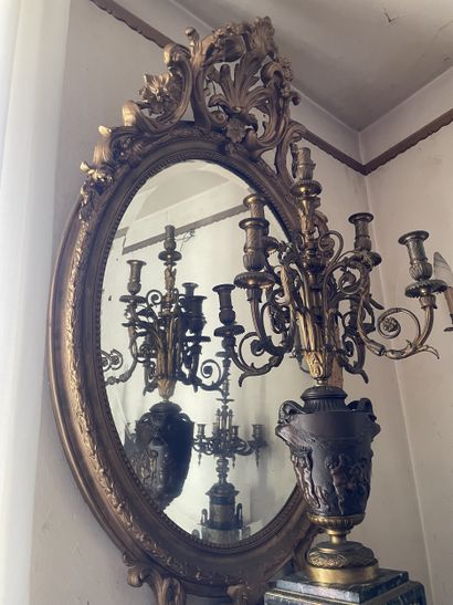 Miroir ovale en bois stuqué et redoré. Le...