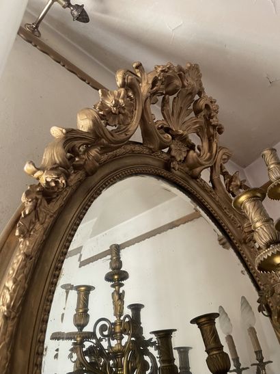 Miroir ovale en bois stuqué et redoré. Le...