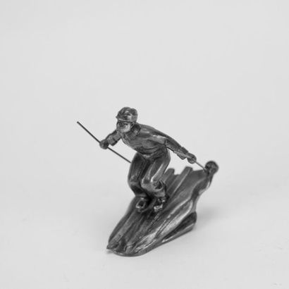 Skier, metal subject. H: 9, D: 8 cm. (a bent...