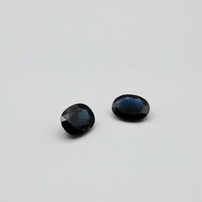 Two dark sapphires on paper of oval cut,...
