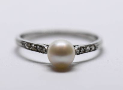 Platinum ring holding a pearl and surrounded...