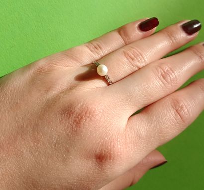 Platinum ring holding a pearl and surrounded...
