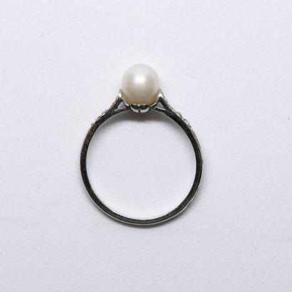 Platinum ring holding a pearl and surrounded...