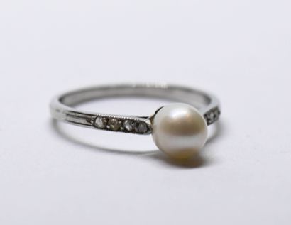 Platinum ring holding a pearl and surrounded...