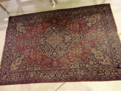 Tapis à motif d'un médaillon rouge. La bordure...
