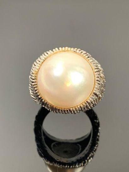 Large bague en or blanc ornée d'une demi-perle.

Tour...