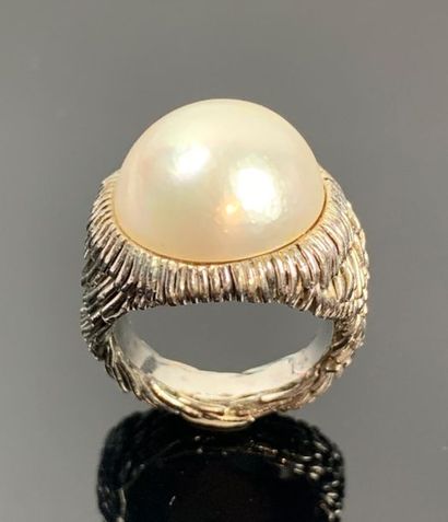 Large bague en or blanc ornée d'une demi-perle.

Tour...
