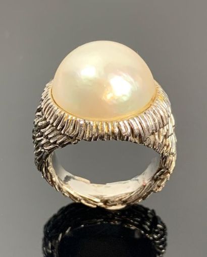 Large bague en or blanc ornée d'une demi-perle.

Tour...