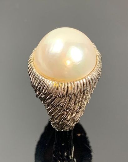 Large bague en or blanc ornée d'une demi-perle.

Tour...
