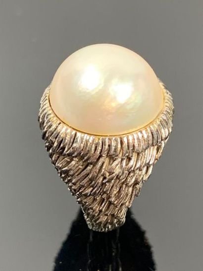 Large bague en or blanc ornée d'une demi-perle.

Tour...