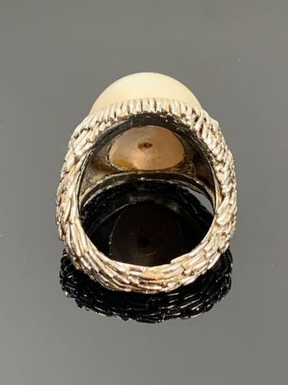 Large bague en or blanc ornée d'une demi-perle.

Tour...