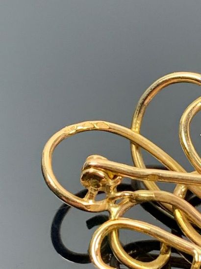 Broche en or jaune figurant des volutes.

H_5...