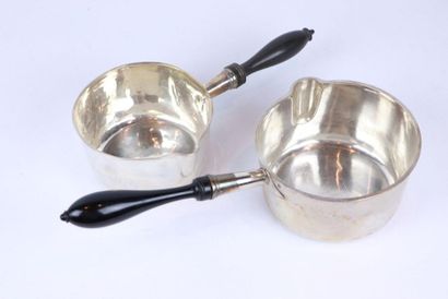 Deux casseroles en argent, tenues par un...