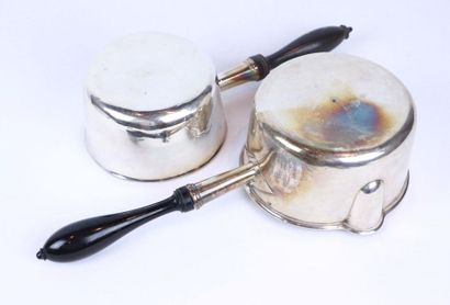 Deux casseroles en argent, tenues par un...