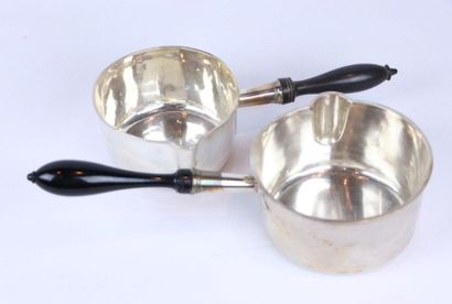 Deux casseroles en argent, tenues par un...