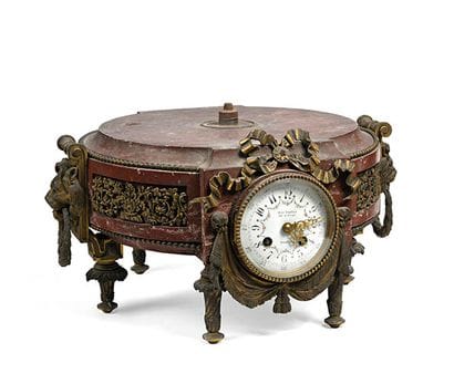 Socle cylindrique en marbre rouge, une pendule...
