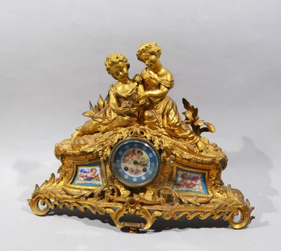 A mantelpiece clock surmounted by two young...