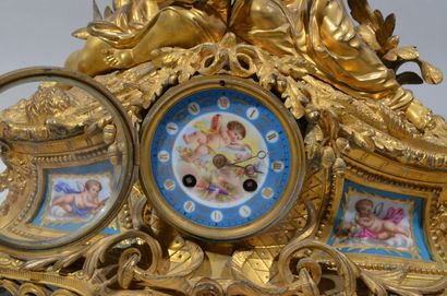 A mantelpiece clock surmounted by two young...