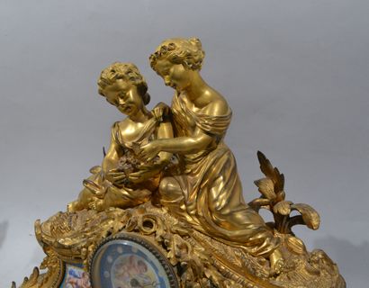 A mantelpiece clock surmounted by two young...
