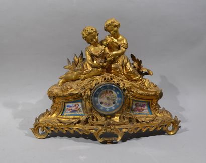 A mantelpiece clock surmounted by two young...