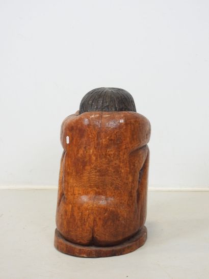 Wood sculpture of a seated, curled-up figure....