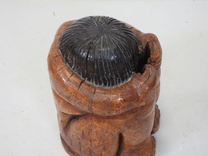 Wood sculpture of a seated, curled-up figure....