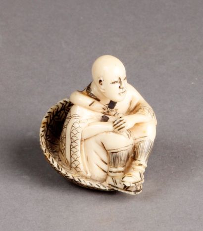 NETSUKE en ivoire représentant un homme assis...