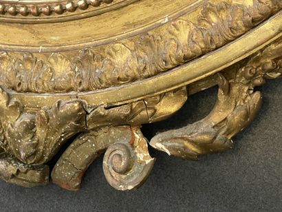 Oval mirror in wood and gilded stucco. Pediment...