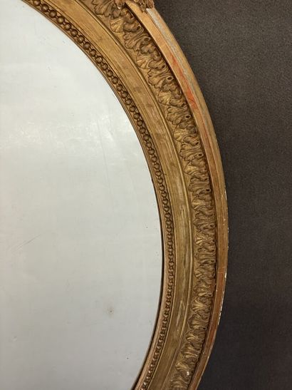 Oval mirror in wood and gilded stucco. Pediment...