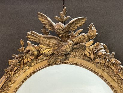 Oval mirror in wood and gilded stucco. Pediment...