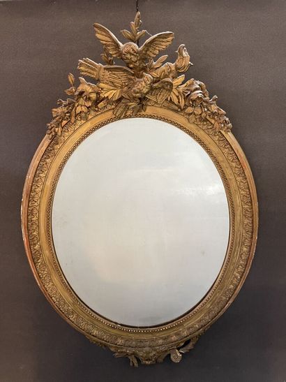Oval mirror in wood and gilded stucco. Pediment...