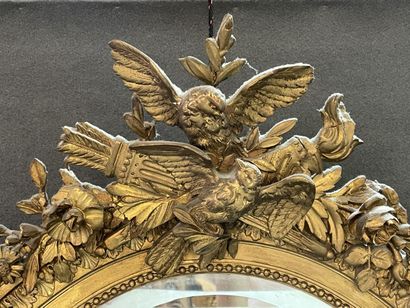 Oval mirror in wood and gilded stucco. Pediment...
