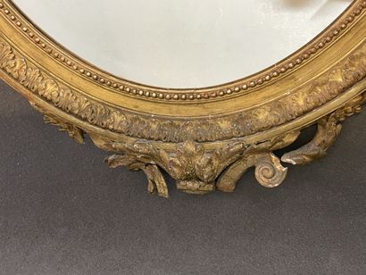 Oval mirror in wood and gilded stucco. Pediment...