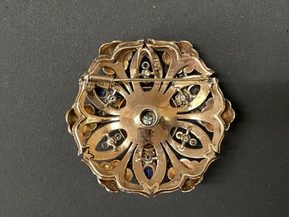 A circular pendant brooch depicting a flower...