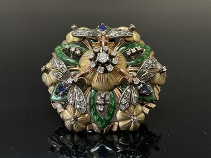A circular pendant brooch depicting a flower...