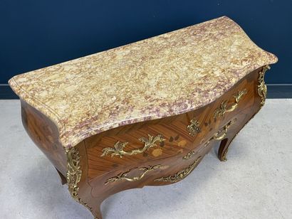 Commode galbée marquetée ouvrant à deux tiroirs.
Style...
