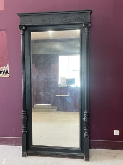 Miroir dans un cadre en bois noirci à colonnes....