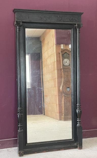 Miroir dans un cadre en bois noirci à colonnes....