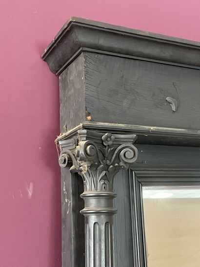 Miroir dans un cadre en bois noirci à colonnes....