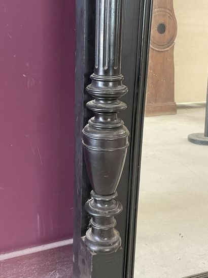 Miroir dans un cadre en bois noirci à colonnes....