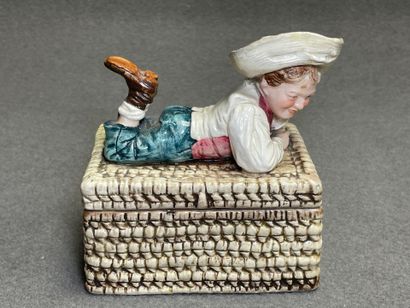 Boite en barbotine figurant un enfant allongé...