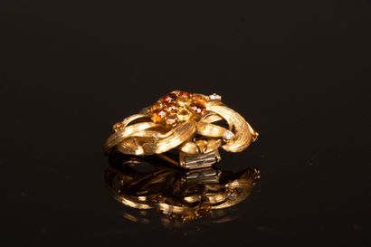Gold brooch featuring a stylized flower set...