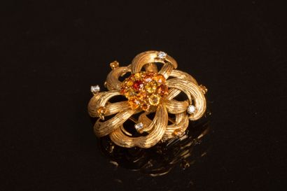 Gold brooch featuring a stylized flower set...