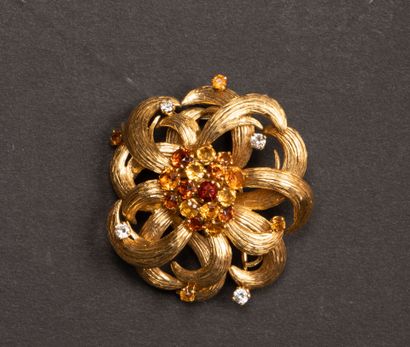 Gold brooch featuring a stylized flower set...